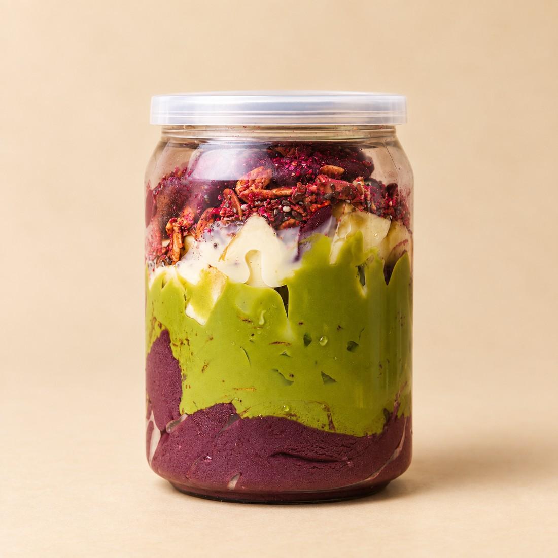 Acai Pistachio Paradise in a clear jar on a cream studio background
