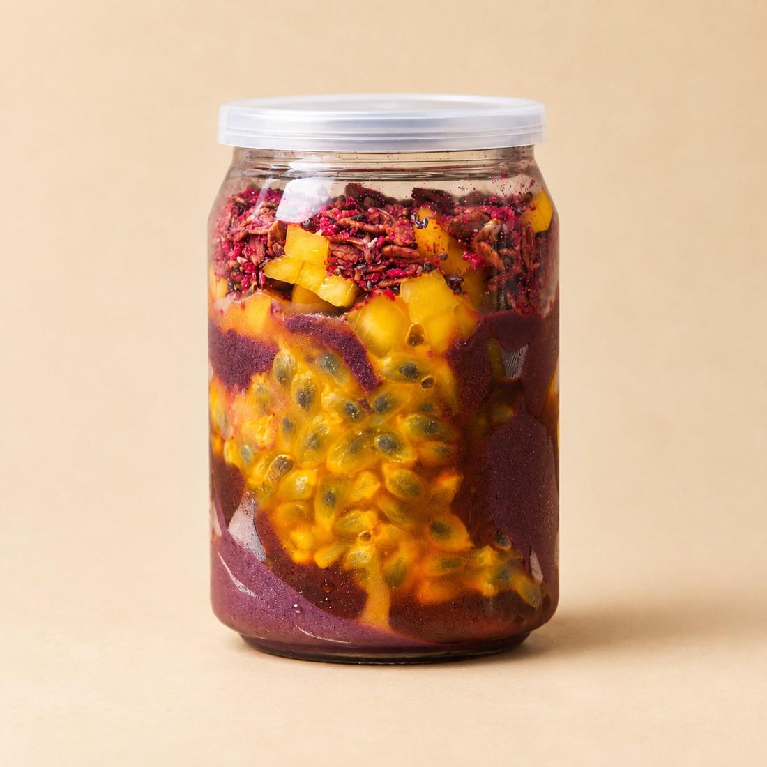 Acai Tropique in a clear jar on a cream studio background