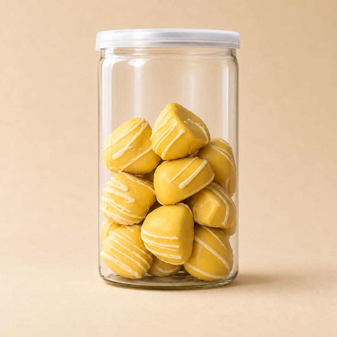 Yellow mango and passion fruit dome bites arranged in a clear CRMY confectionery jar