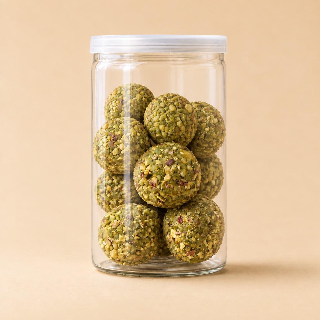 Pistachio-coated vegan truffle bites arranged in a clear CRMY confectionery jar