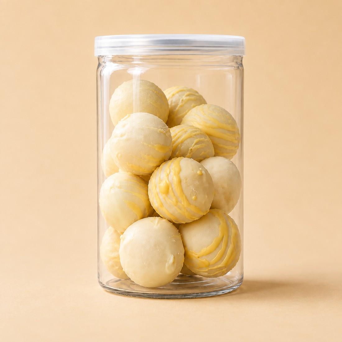Pale mango and passion fruit truffle bites with yellow decoration in a clear CRMY confectionery jar